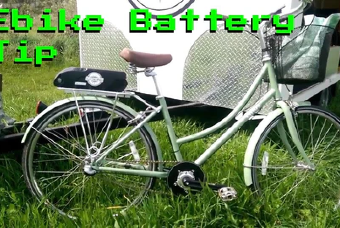 Mint green e-bike with a front basket, rear rack, and a downtube battery.